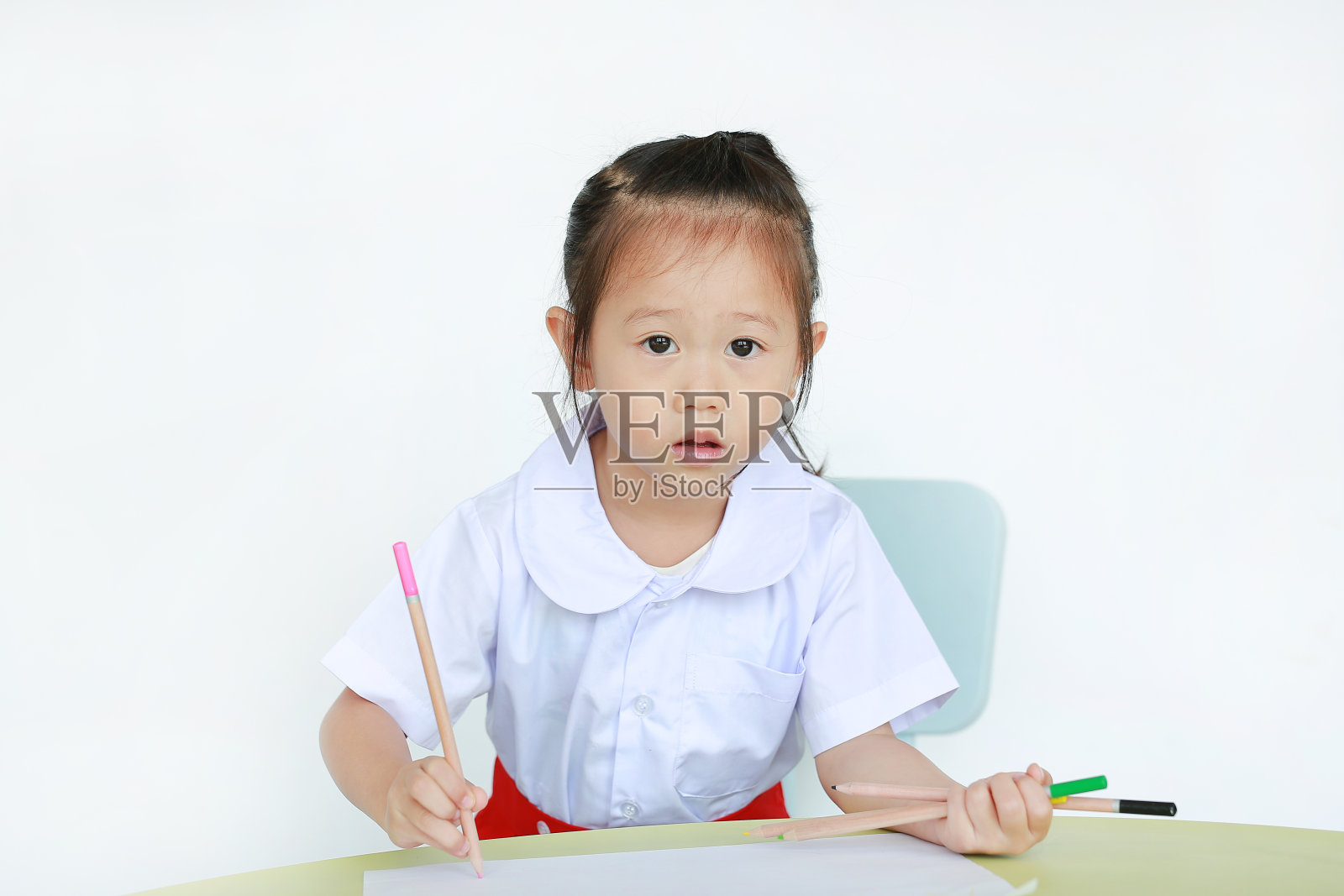 亚洲儿童在校服与铅笔写在桌子上孤立的白色背景。照片摄影图片
