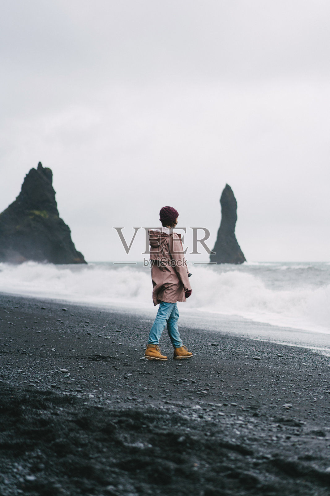 一名女子走在冰岛维克的黑色沙滩上照片摄影图片