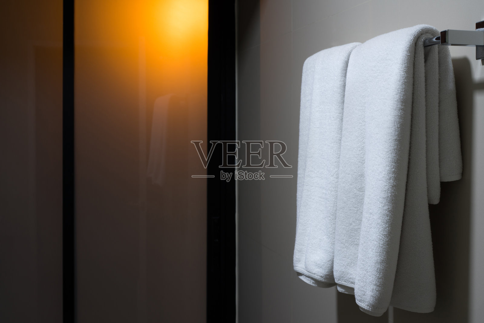 空荡荡的浴室里，白毛巾挂在衣架上照片摄影图片
