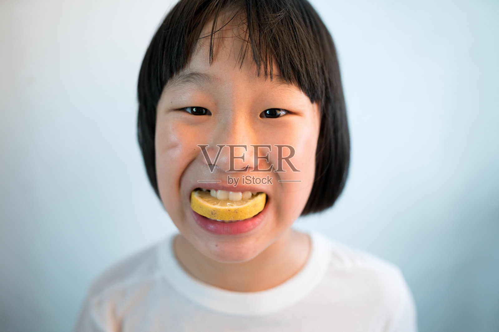 初级亚洲女性嘴里含着一片柠檬照片摄影图片