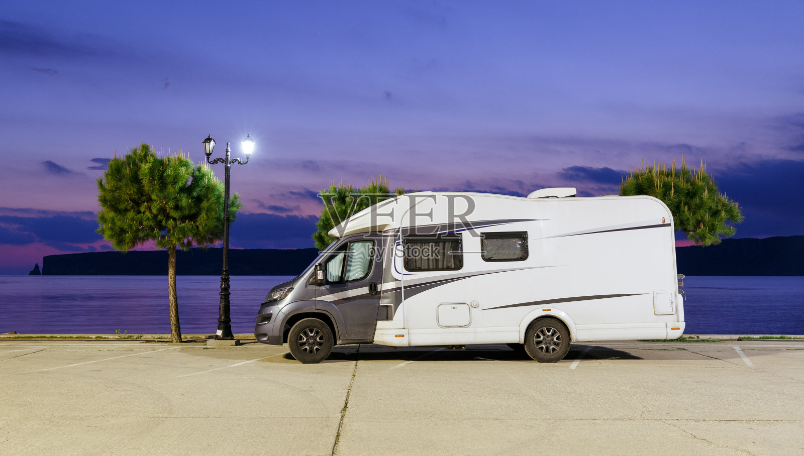 房车和露营车停在海滩上。房车停放在希腊爱琴海边的一个房车停车场上。晚上的风景。照片摄影图片