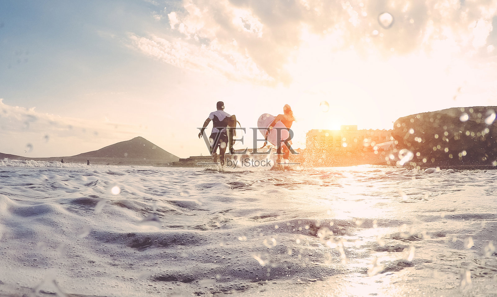 冲浪者夫妇与冲浪板在海滩上跑步-运动的人在阳光明媚的日子里有乐趣-极限运动，旅行和度假的概念-关注身体-水在镜头照片摄影图片