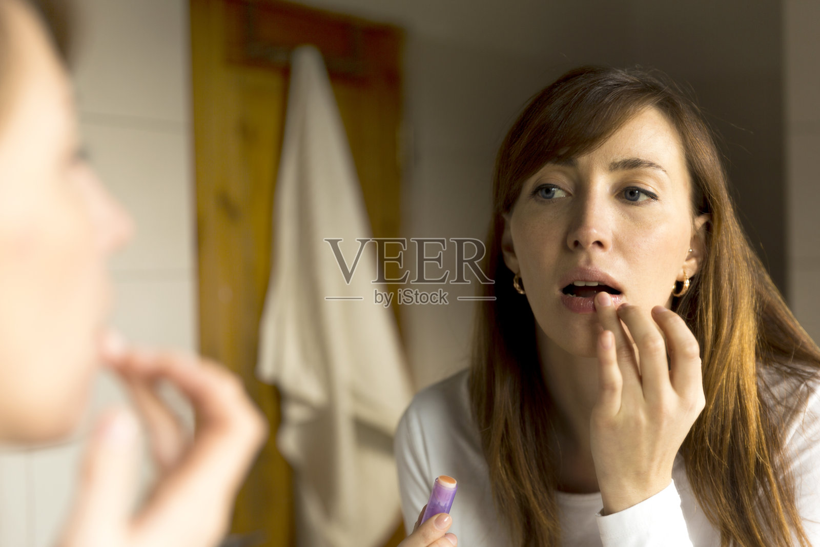 嘴唇护理。在浴室里涂唇膏的女人照片摄影图片