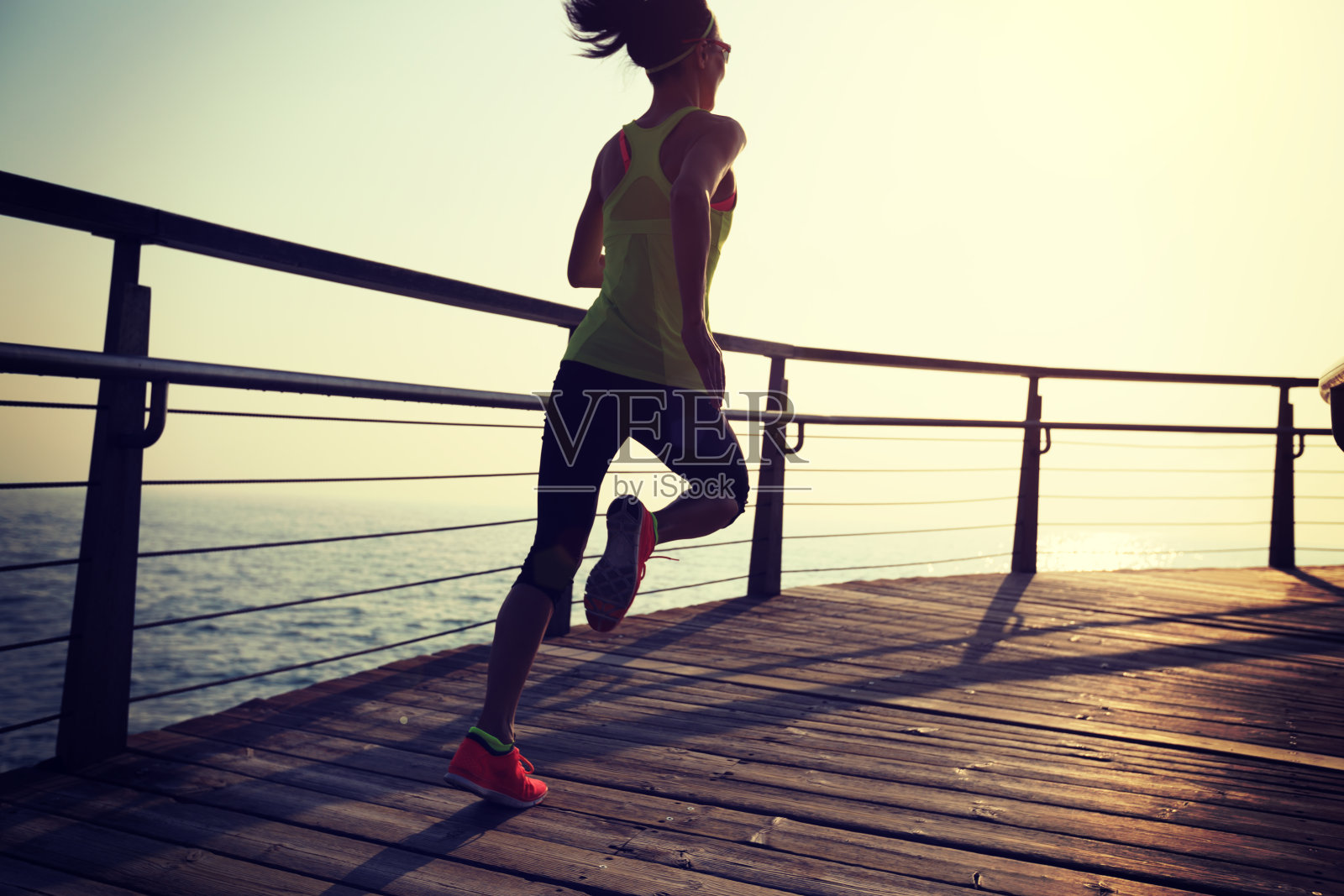 运动健身女性跑步在海滨木板路在日出照片摄影图片