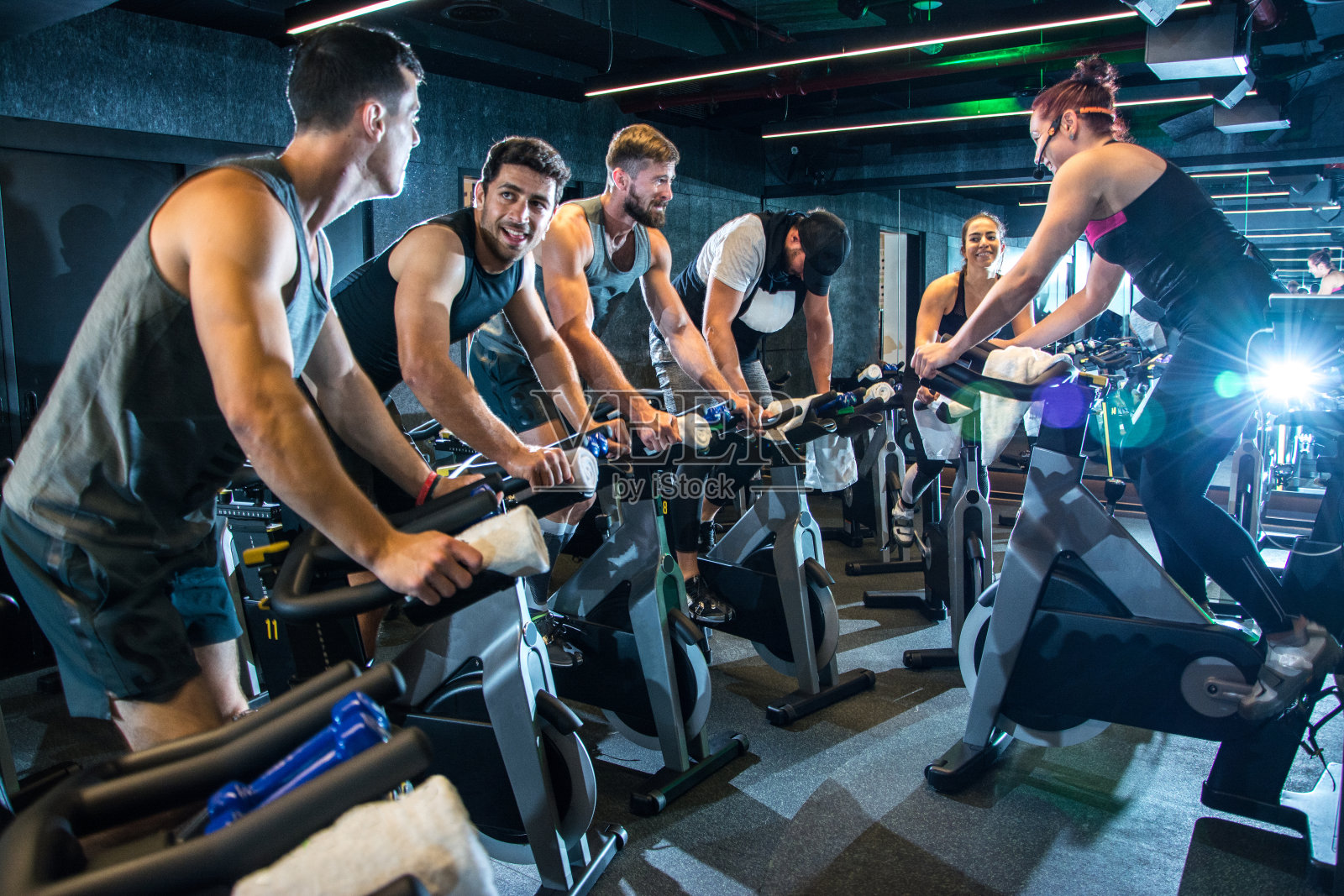 一群快乐的运动人士在健身房一起骑动感单车。照片摄影图片