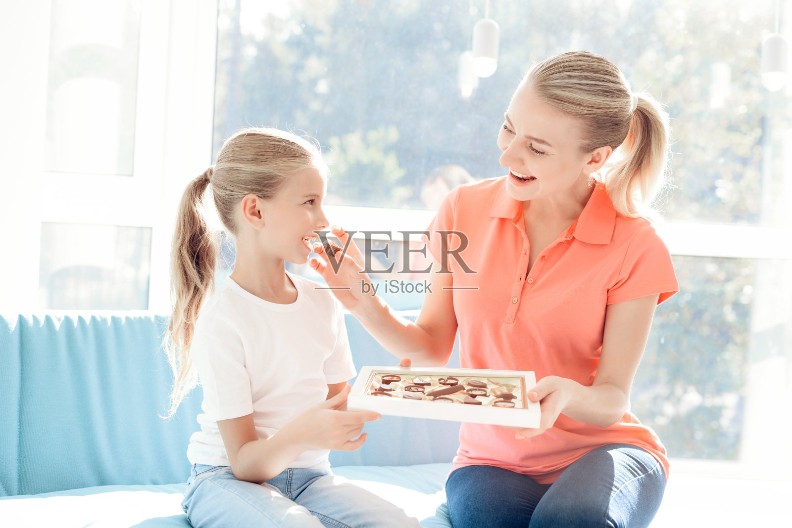 女孩为她母亲准备了一个惊喜。女儿给了母亲一盒巧克力。照片摄影图片
