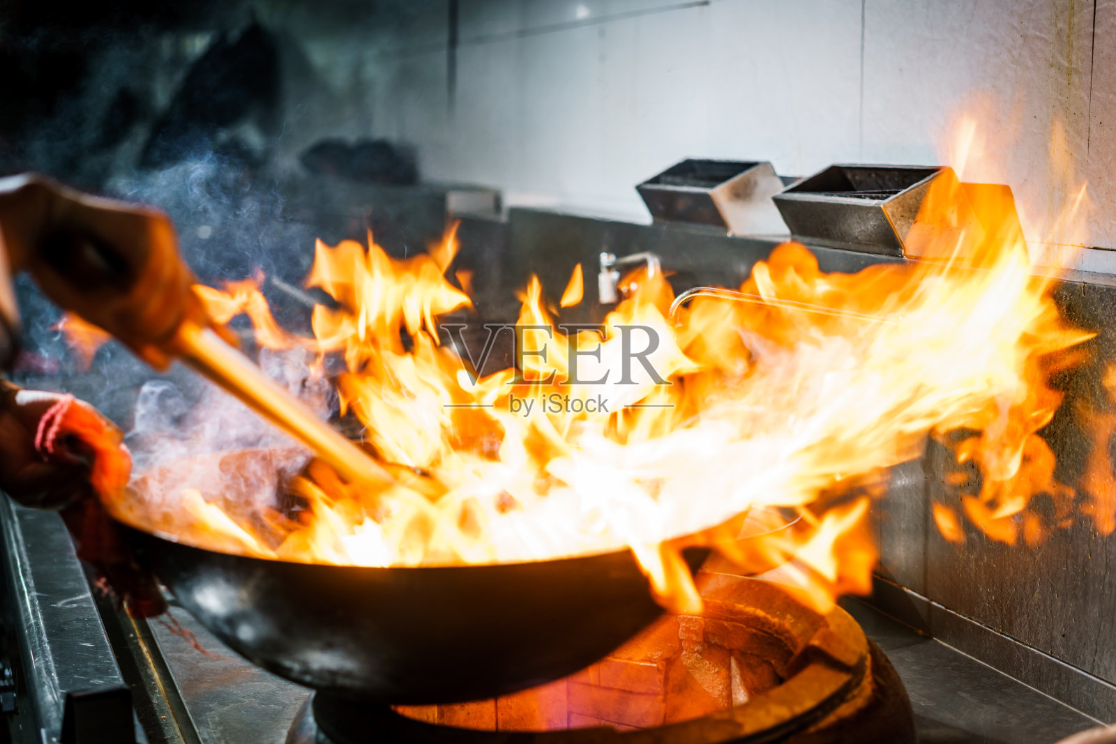 厨师在餐厅厨房的炉子上燃烧着熊熊的火焰照片摄影图片