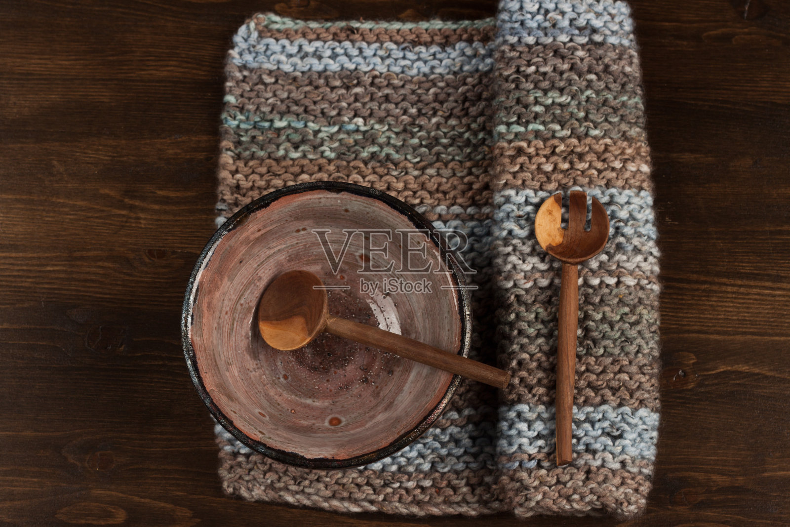 黑色木桌上的乡村陶瓷碗，针织面料和木制汤匙照片摄影图片