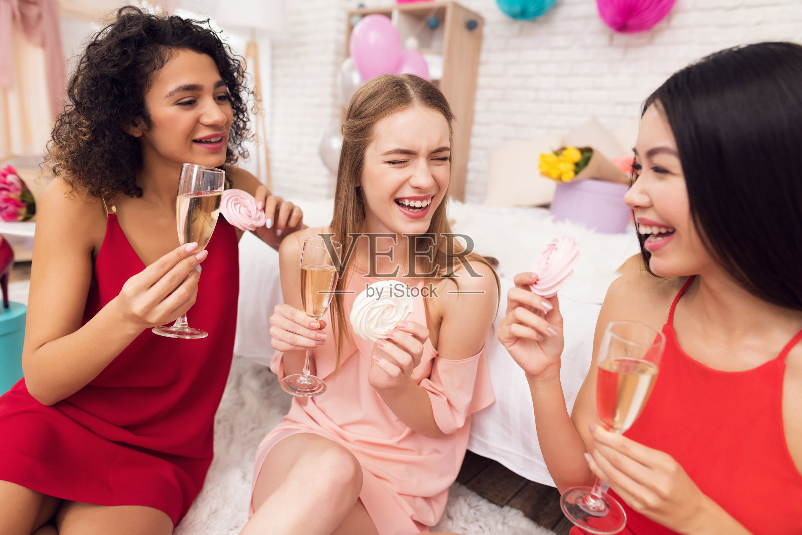 三个女孩拿着饼干和香槟。他们正在庆祝3月8日的妇女节。照片摄影图片