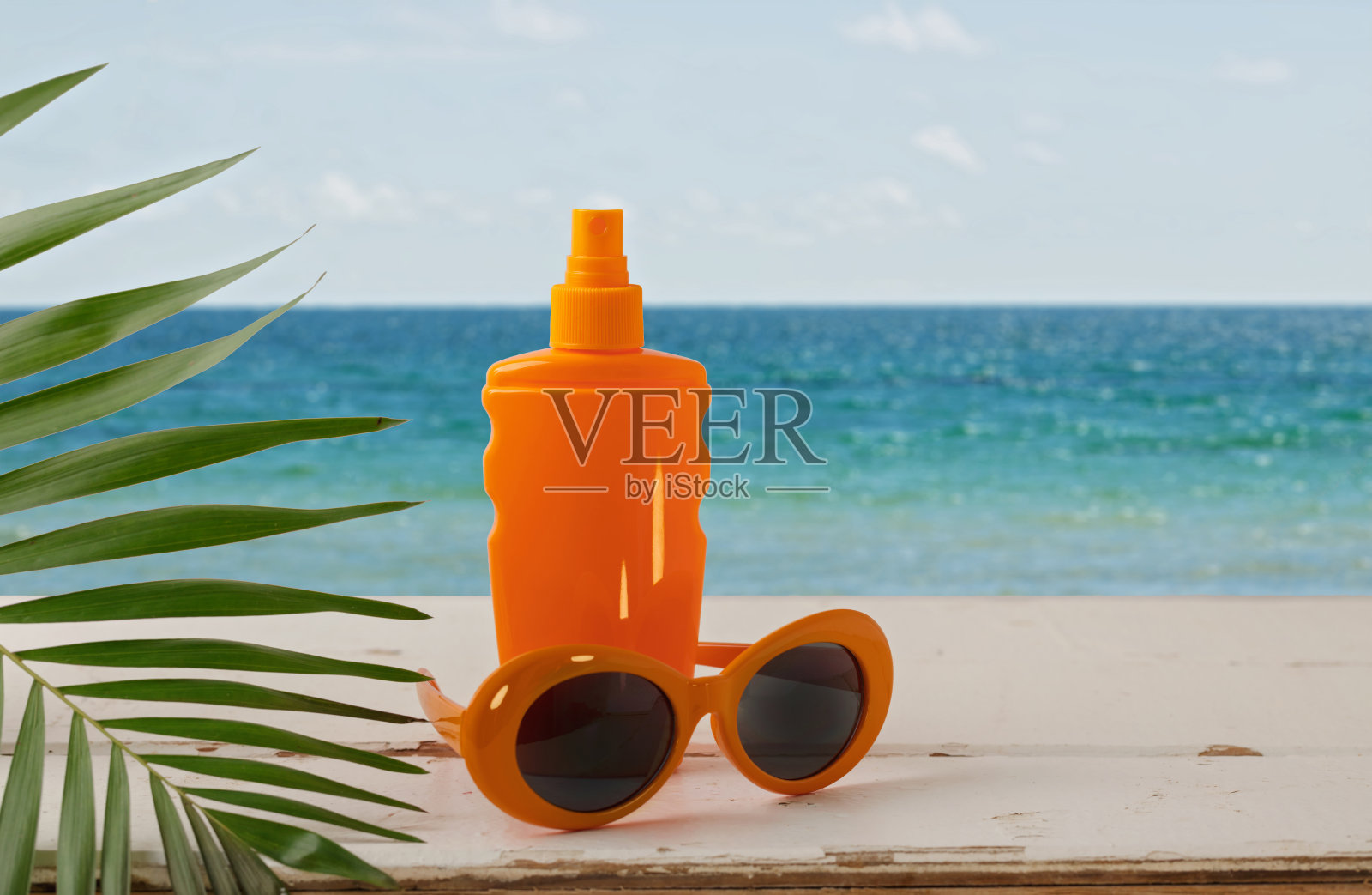 夏天的海景。在沙滩上放松，涂抹防晒霜，戴上帽子和橙色太阳镜。照片摄影图片