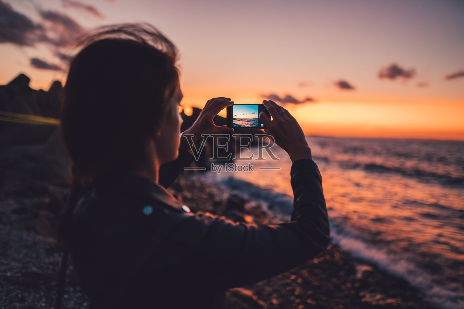 在海滩上拍摄日落的女人照片摄影图片