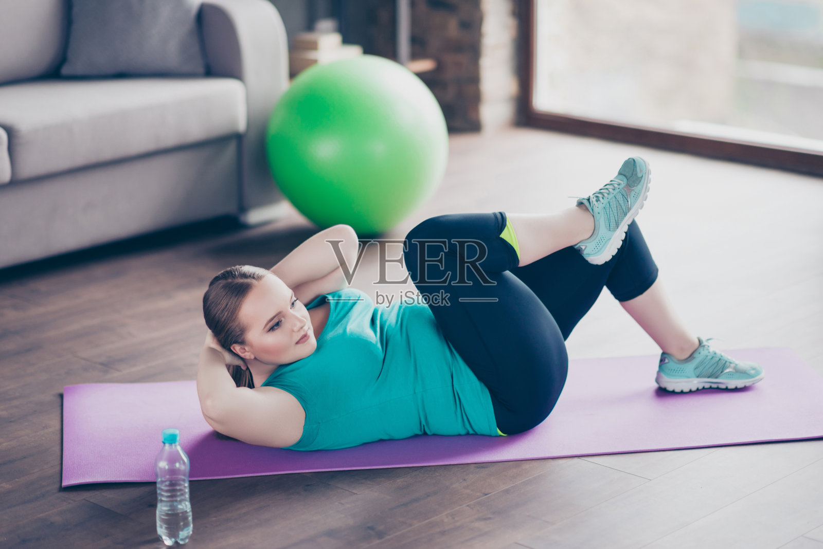 开朗活跃兴奋集中积极的模特胖女人正在改善她的腹部肌肉，她正在做仰卧起坐在家里的地板上照片摄影图片