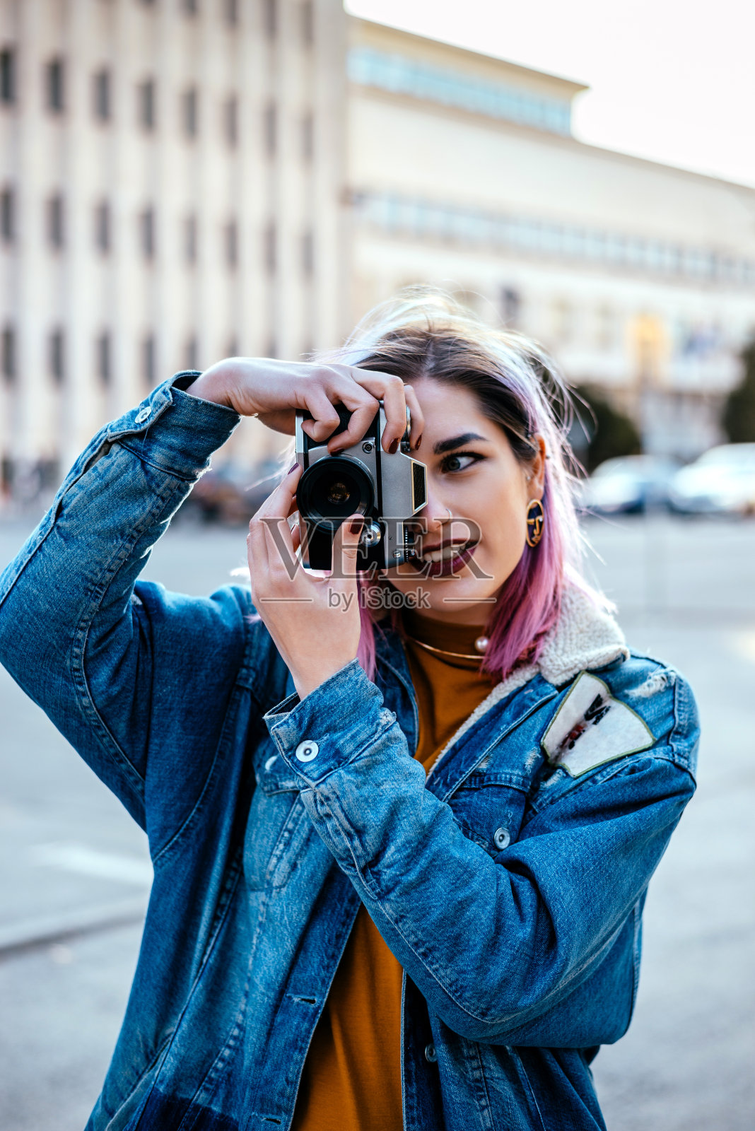 年轻的女摄影师在城市街道上用相机拍照。照片摄影图片