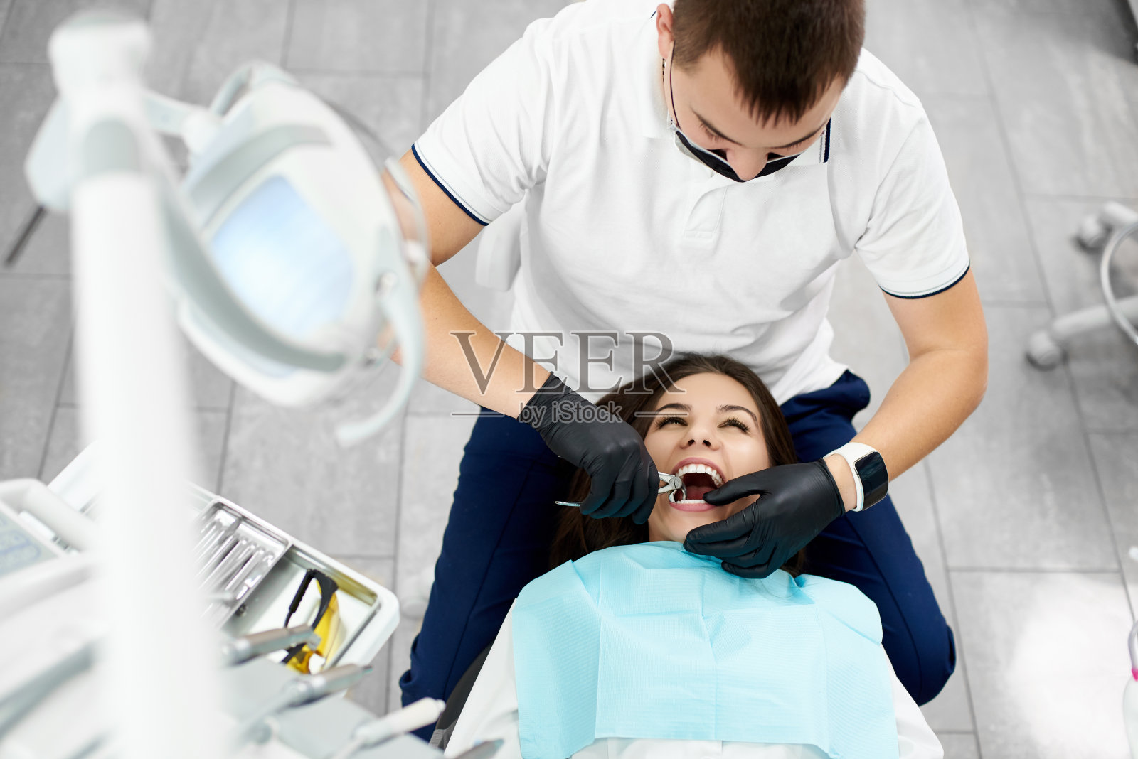 迷人的黑发女子正在一个现代牙科诊所的男性牙医的牙齿。照片摄影图片