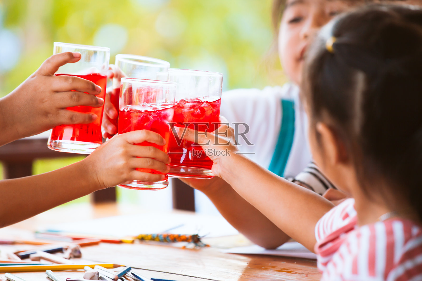一群亚洲儿童在用冰块碰杯新鲜的红果汁水照片摄影图片