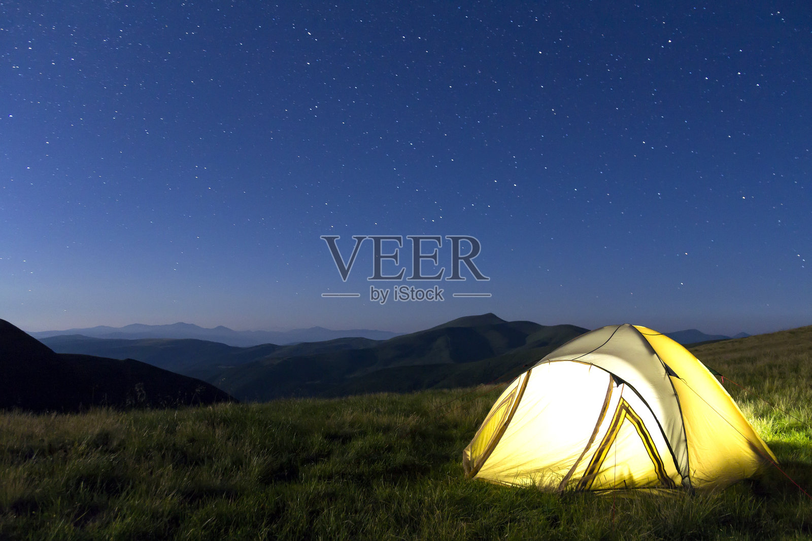 夜晚，星星满天，徒步旅行者在山上搭帐篷照片摄影图片