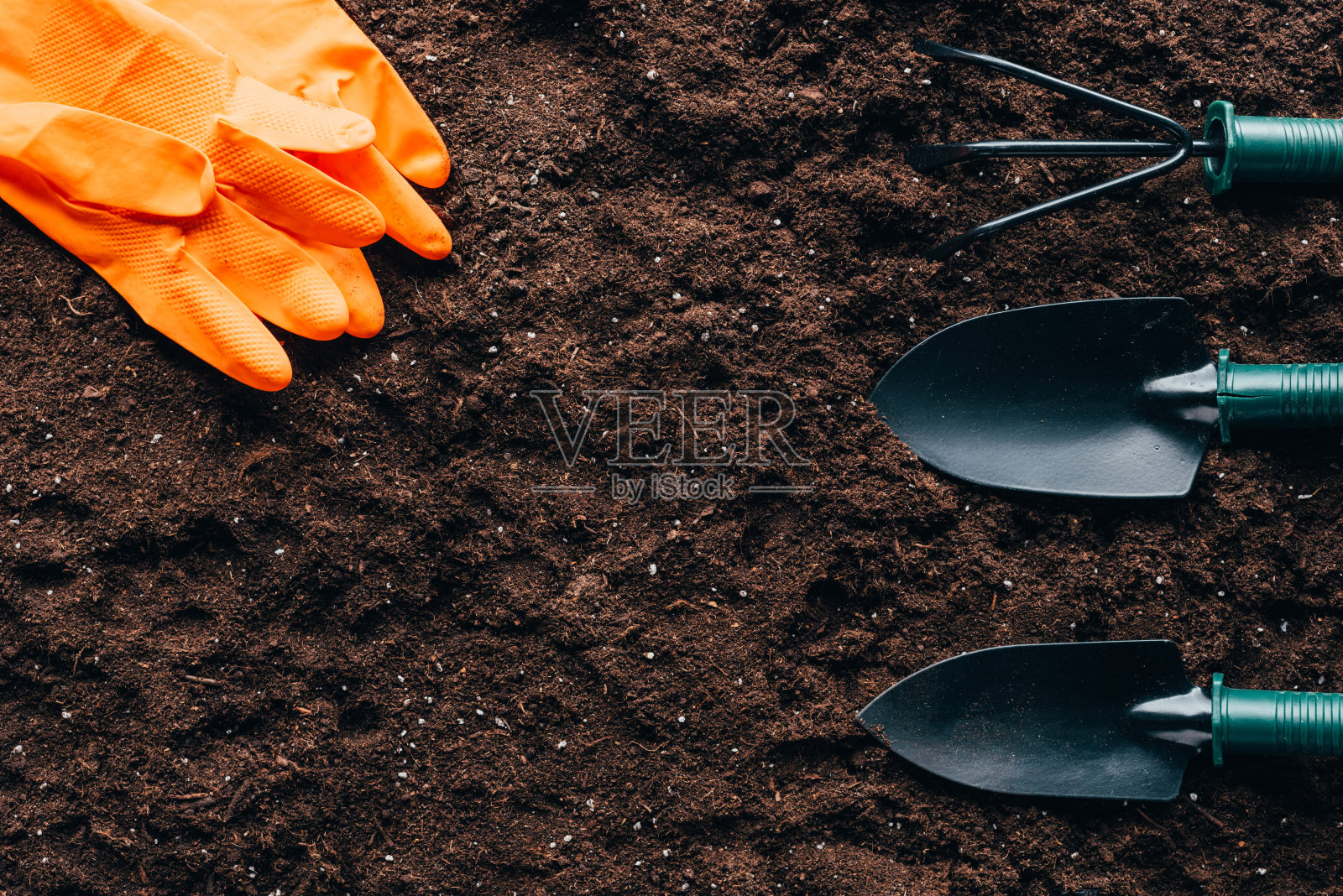 俯视图橙色橡胶手套和土壤上的小园艺工具照片摄影图片