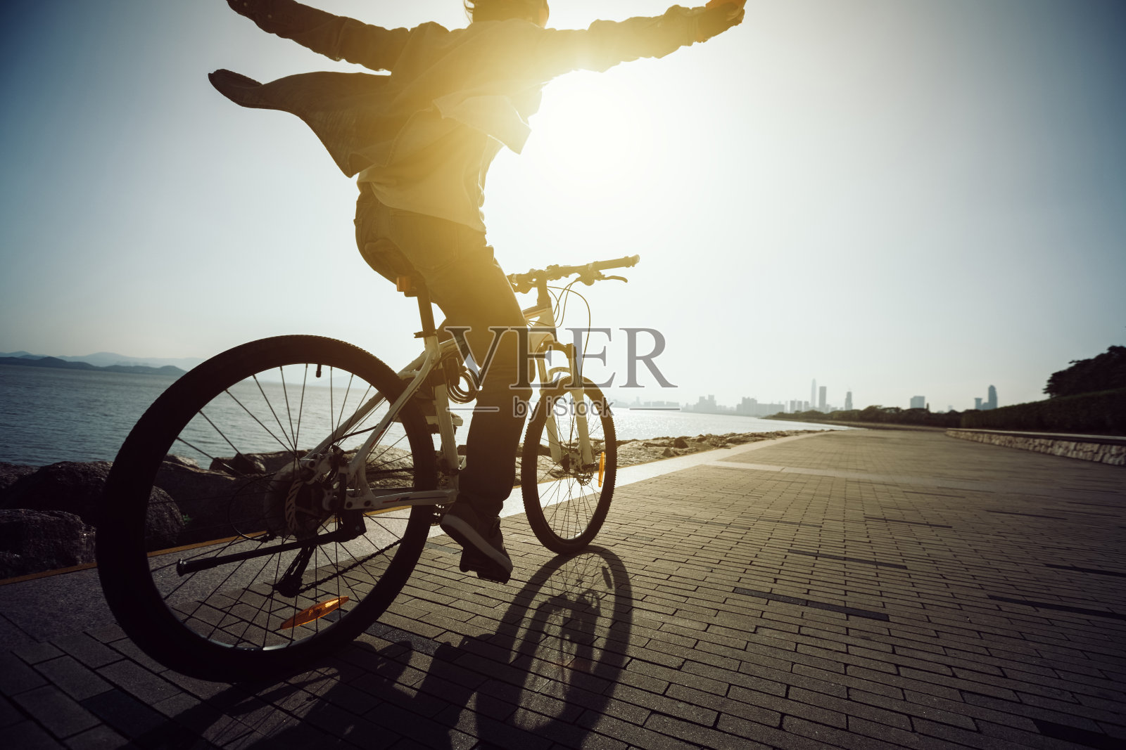 剪影自行车骑在日出的海岸公路上照片摄影图片
