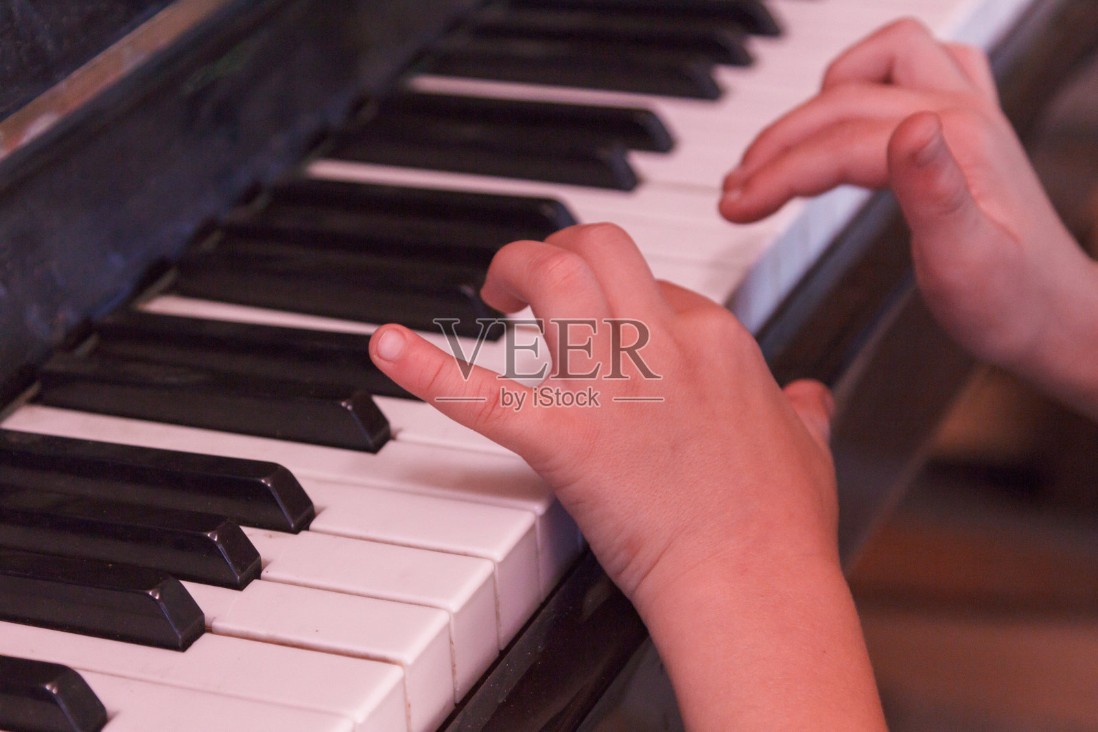 孩子用手弹奏旧钢琴。照片摄影图片