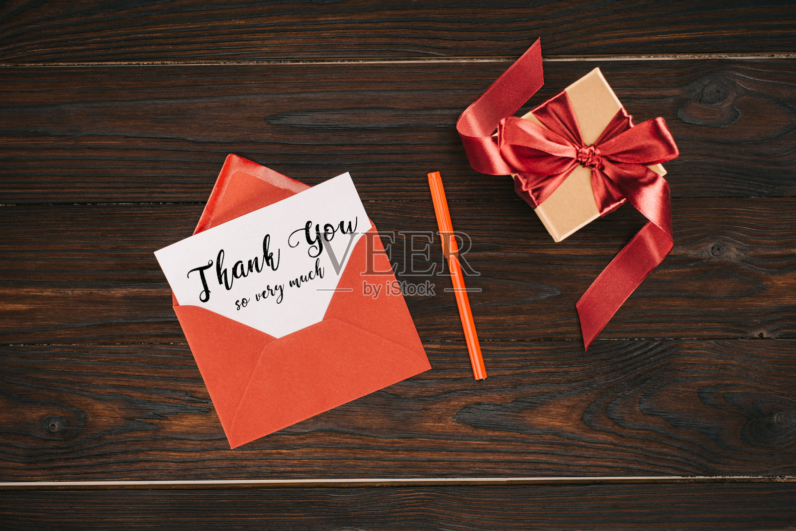 俯视图的红色信封与非常感谢的字母在纸上和礼品盒在木桌上照片摄影图片