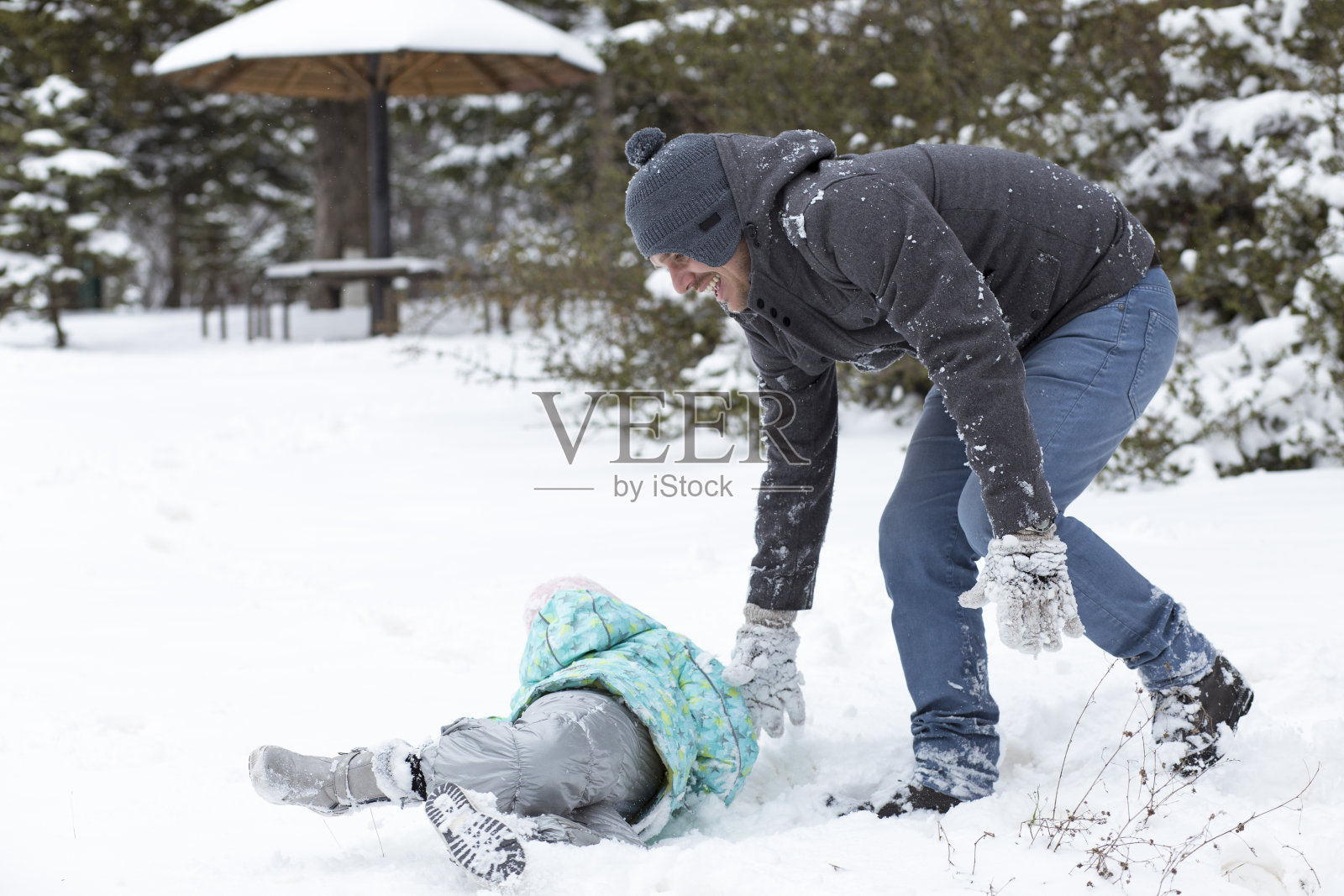 爸爸和妈妈带着他们的孩子，在雪里玩。照片摄影图片