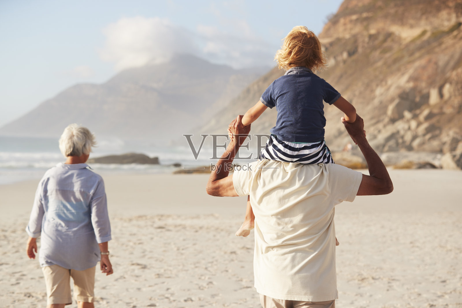 肩上扛孙子的爷爷奶奶在海滩上散步照片摄影图片