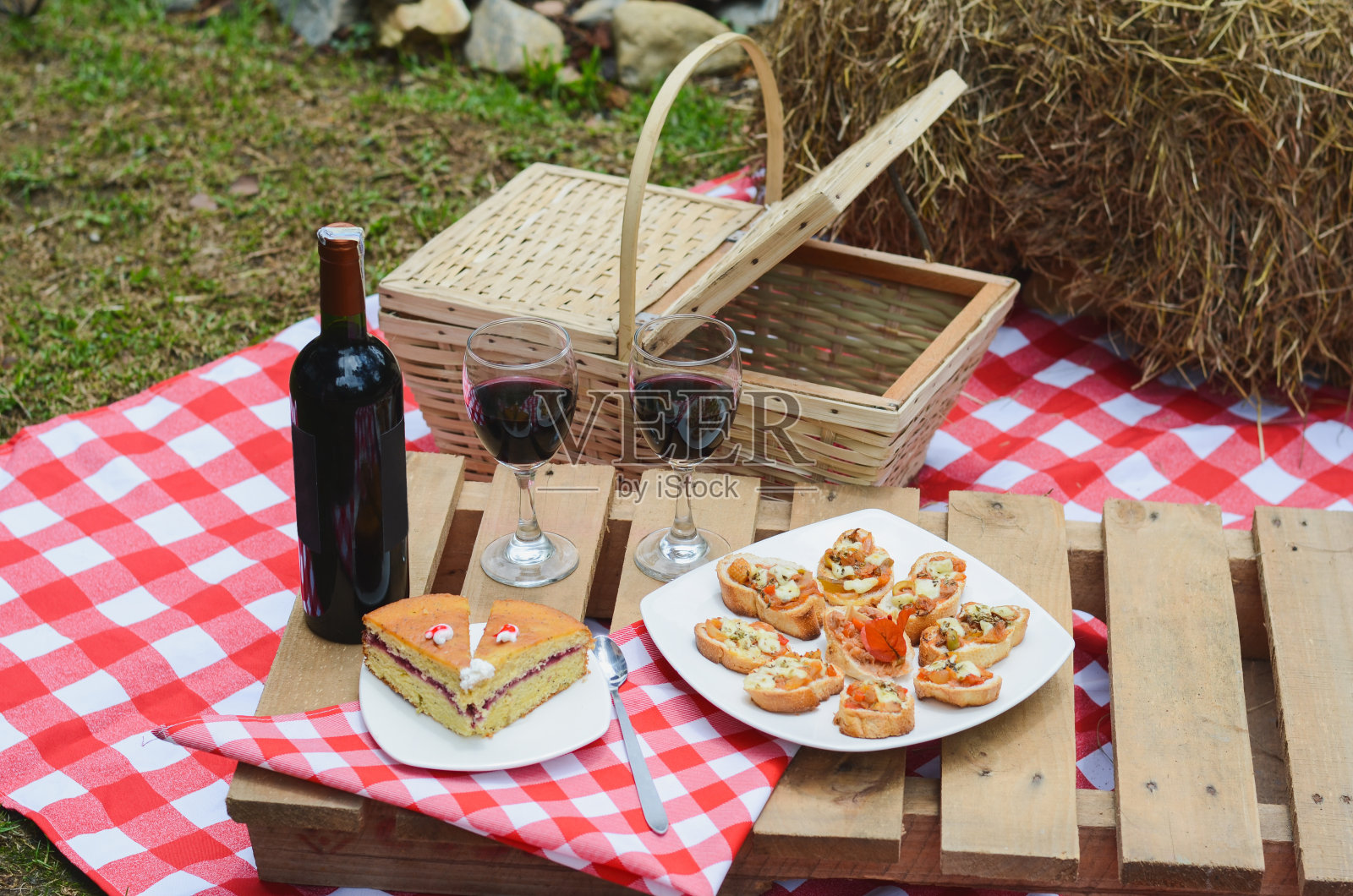 户外野餐，方格桌布和食物篮上放红酒。照片摄影图片