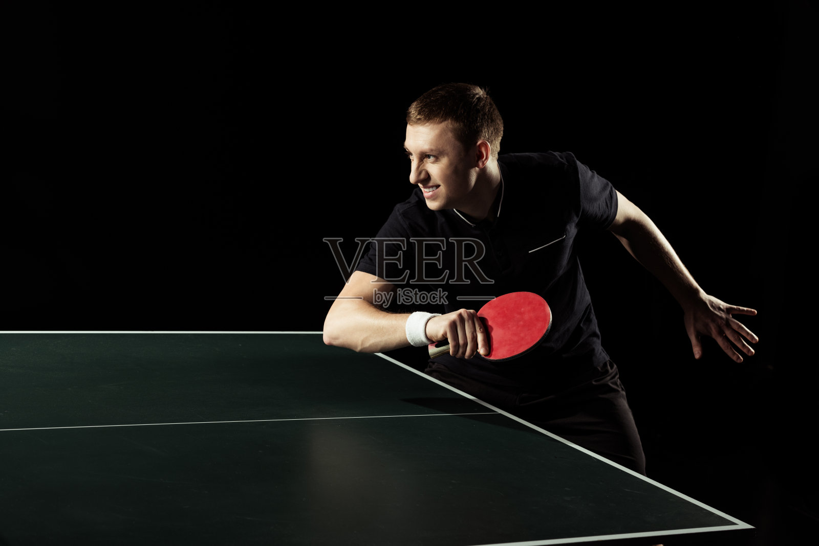 侧视图的年轻网球运动员练习乒乓球孤立在黑色照片摄影图片