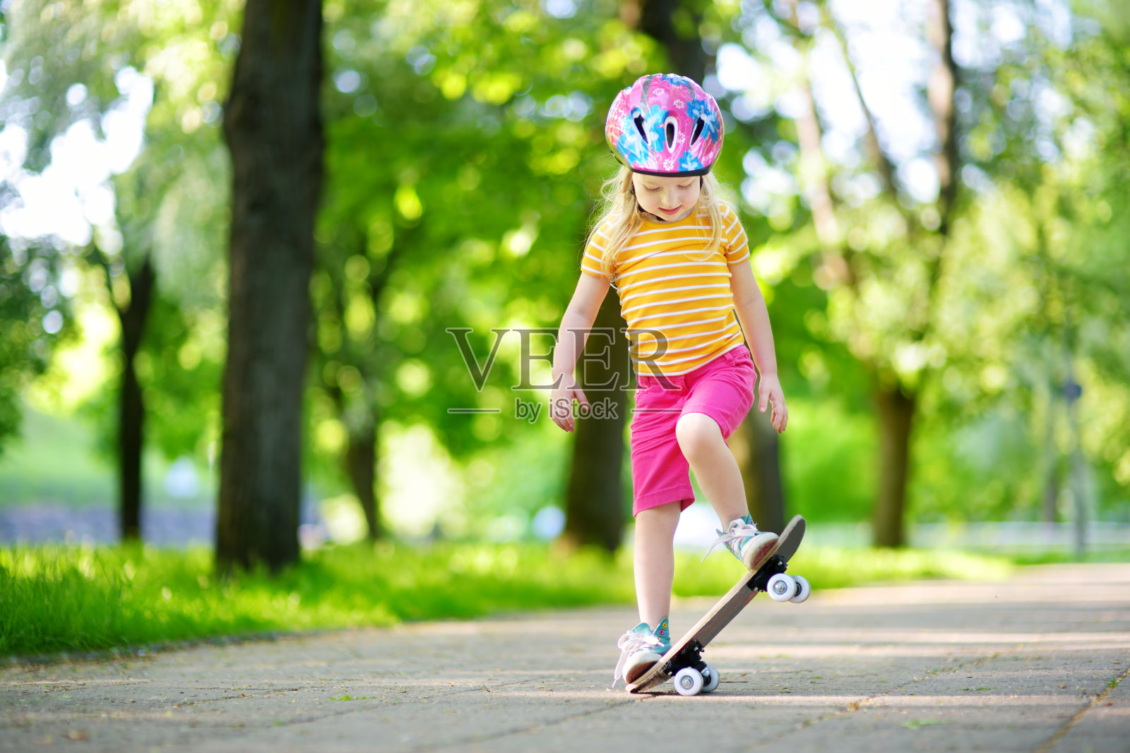 美丽的小女孩在公园里学习滑板在美丽的夏日照片摄影图片