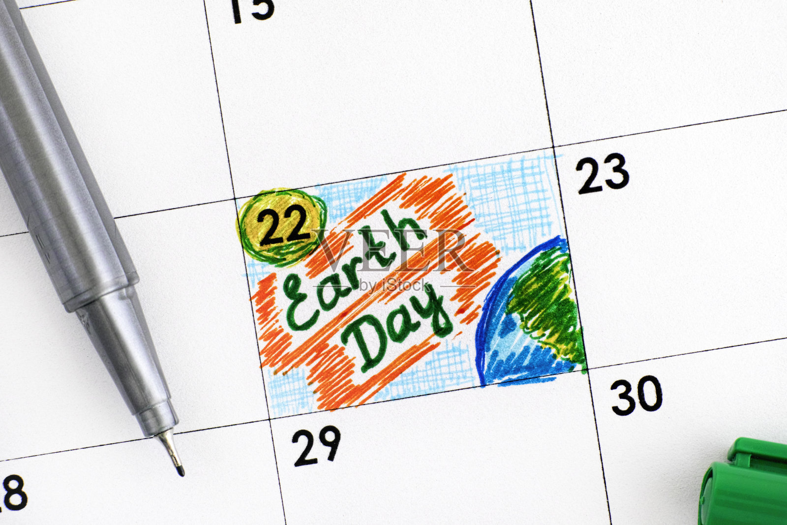 用绿笔在日历上提醒地球日。照片摄影图片