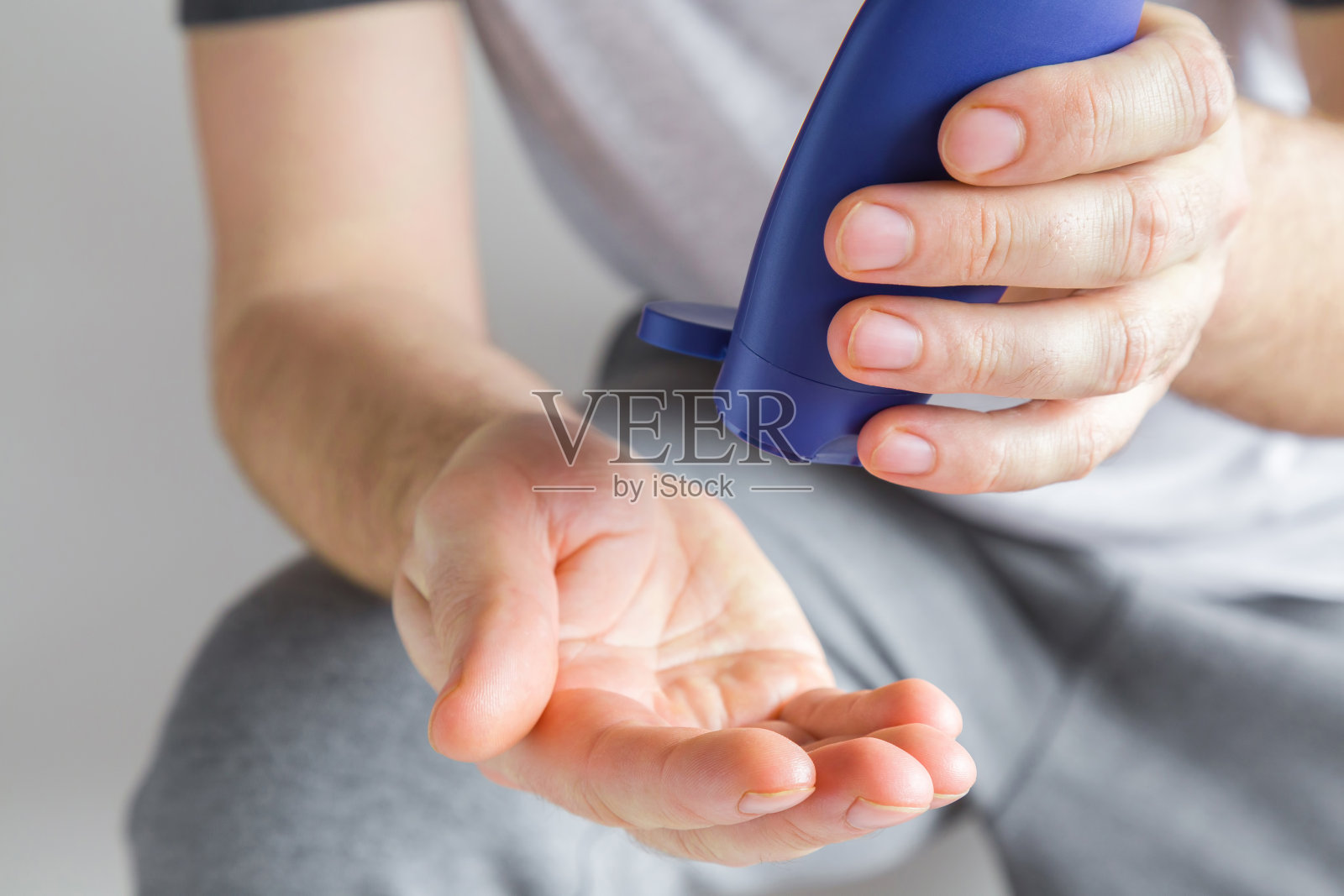 一个手持蓝色塑料管，手上涂着保湿霜的运动员。关心清洁和柔软的手皮肤。医疗保健的概念。照片摄影图片