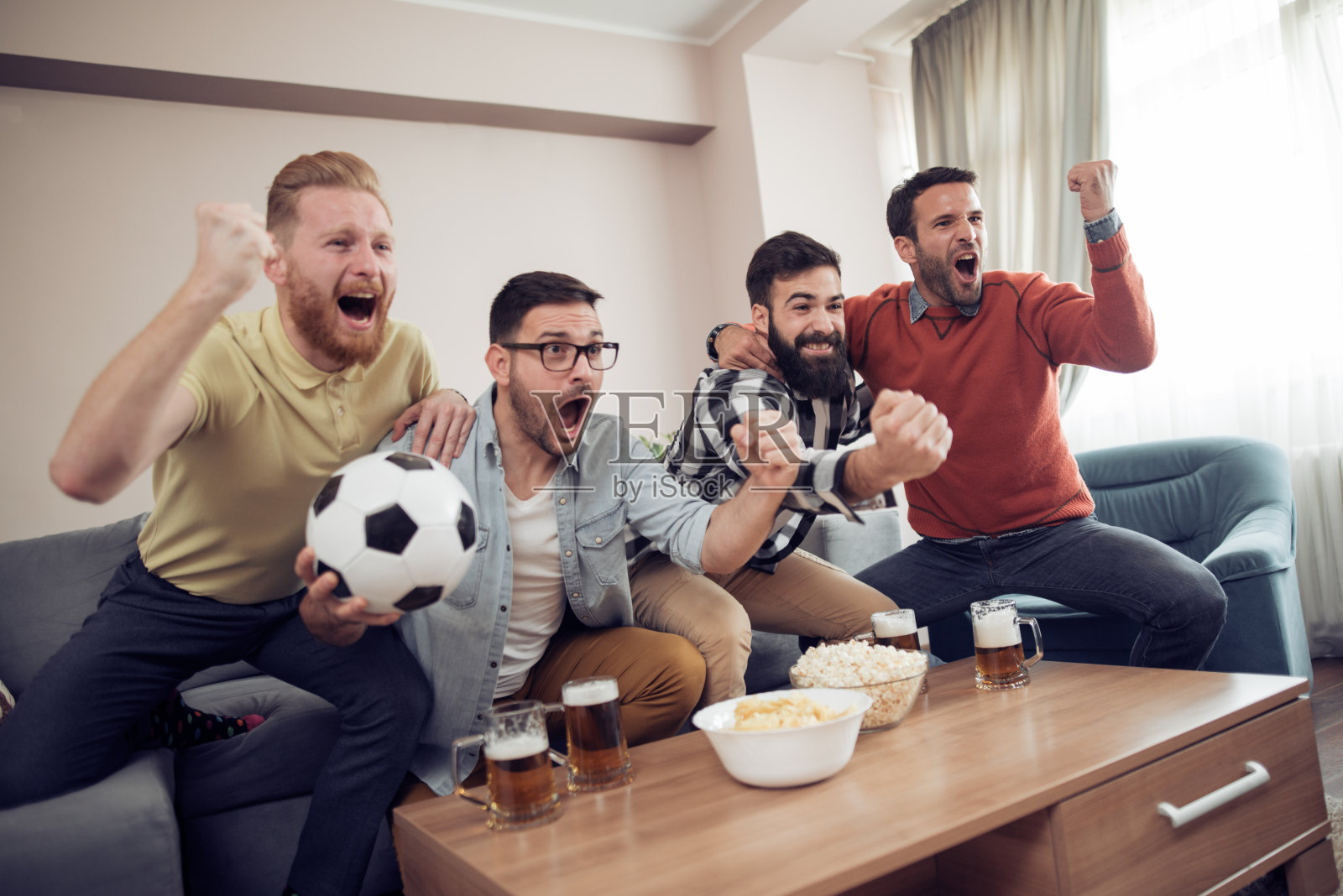 快乐的朋友或球迷在电视上看足球比赛照片摄影图片
