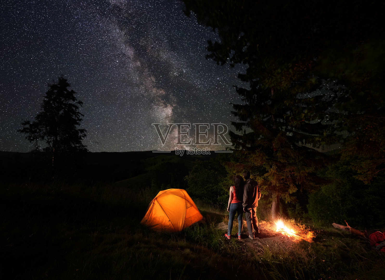 后视图的年轻夫妇看星空与明亮的银河照片摄影图片