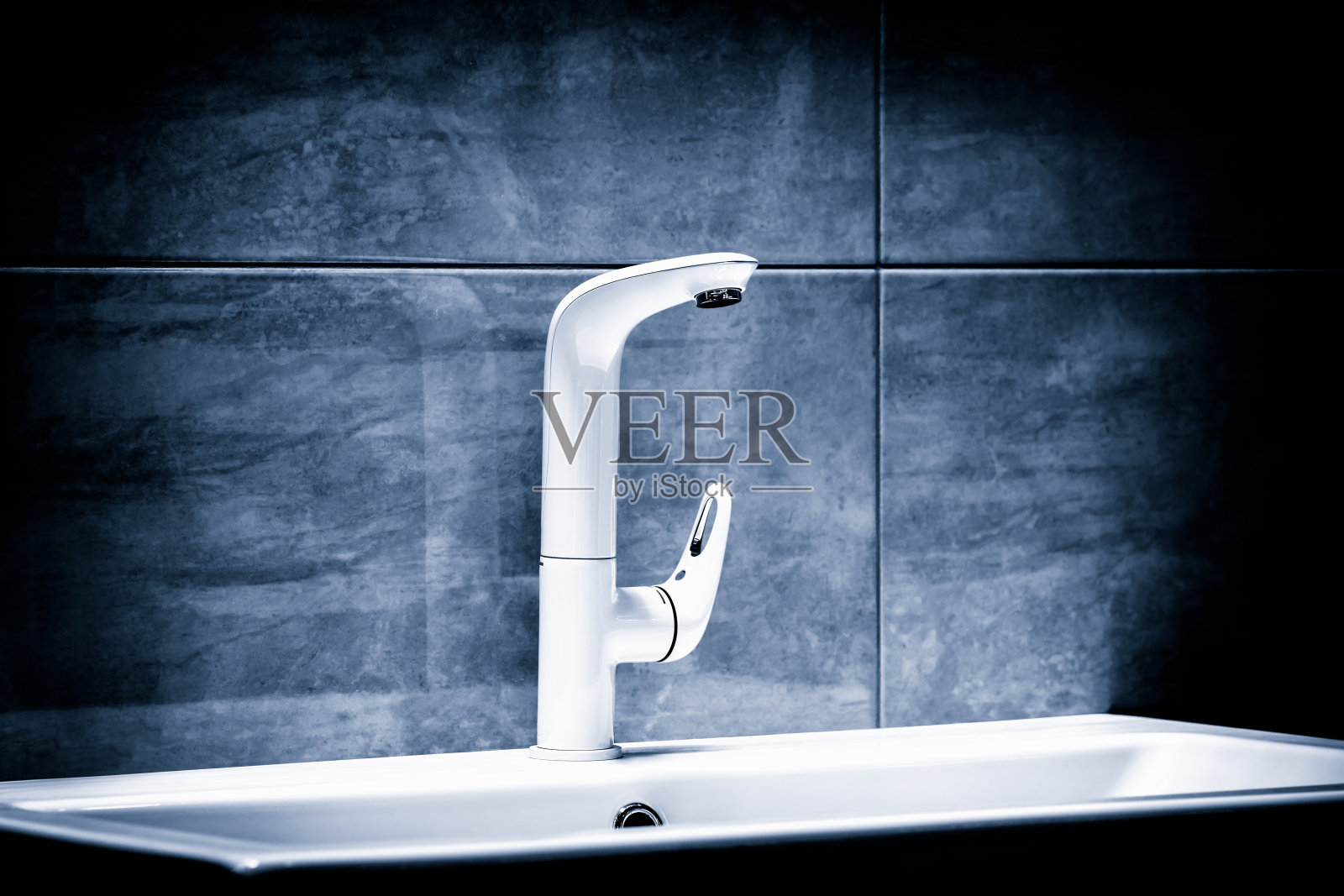 豪华现代风格的白色水龙头搅拌器上的白色水槽在美丽的深蓝色浴室照片摄影图片