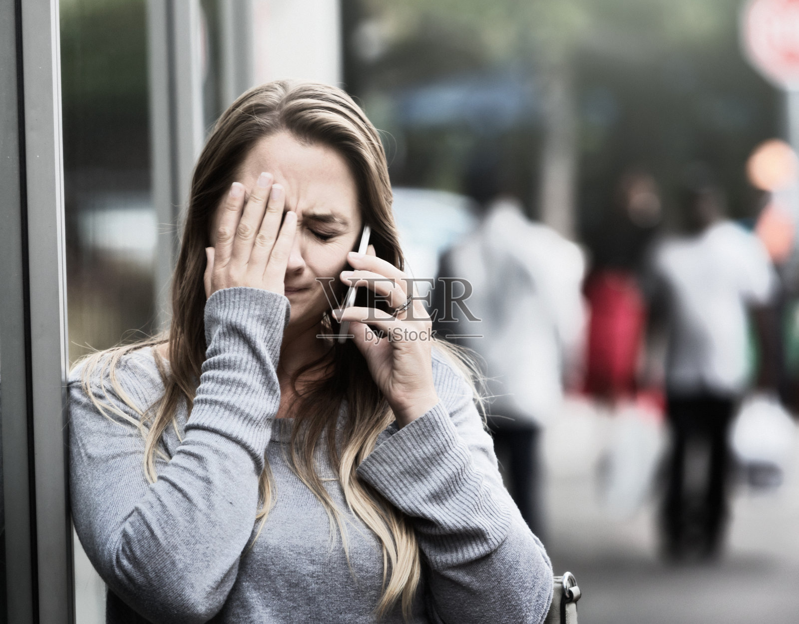 哭泣的女人在街上打电话，很痛苦照片摄影图片