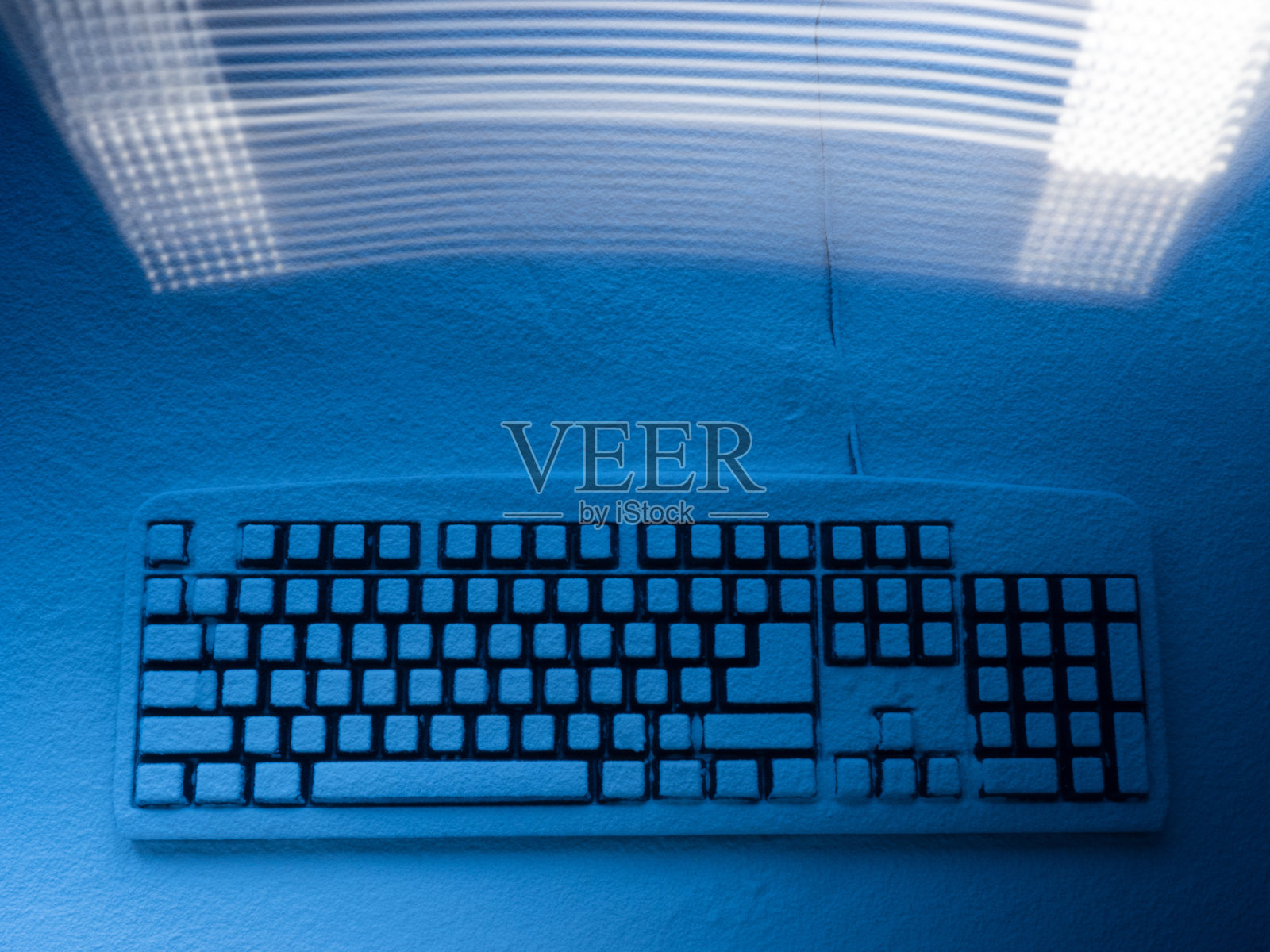 电脑键盘上覆盖着蓝色的雪，上面有来自于freezelight效果的光画的线条痕迹照片摄影图片