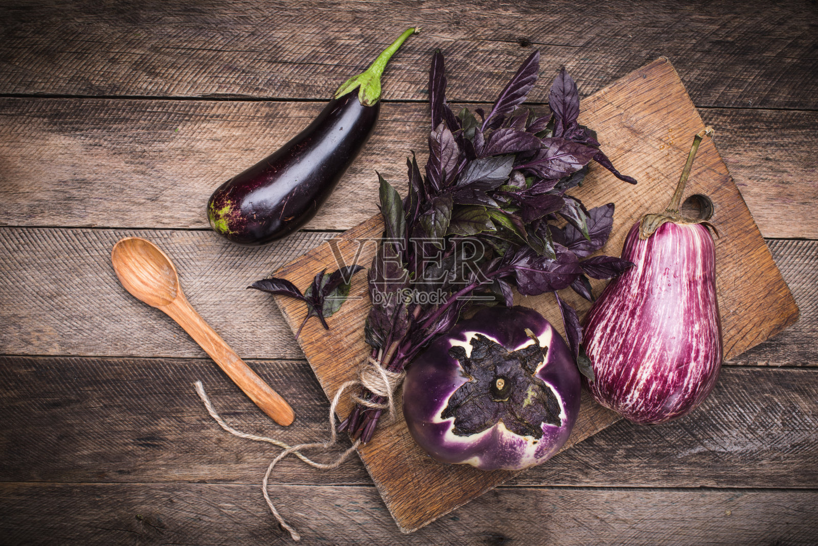 切菜板和木桌上放着茄子、罗勒和勺子。乡村风格和秋天的食物照片照片摄影图片