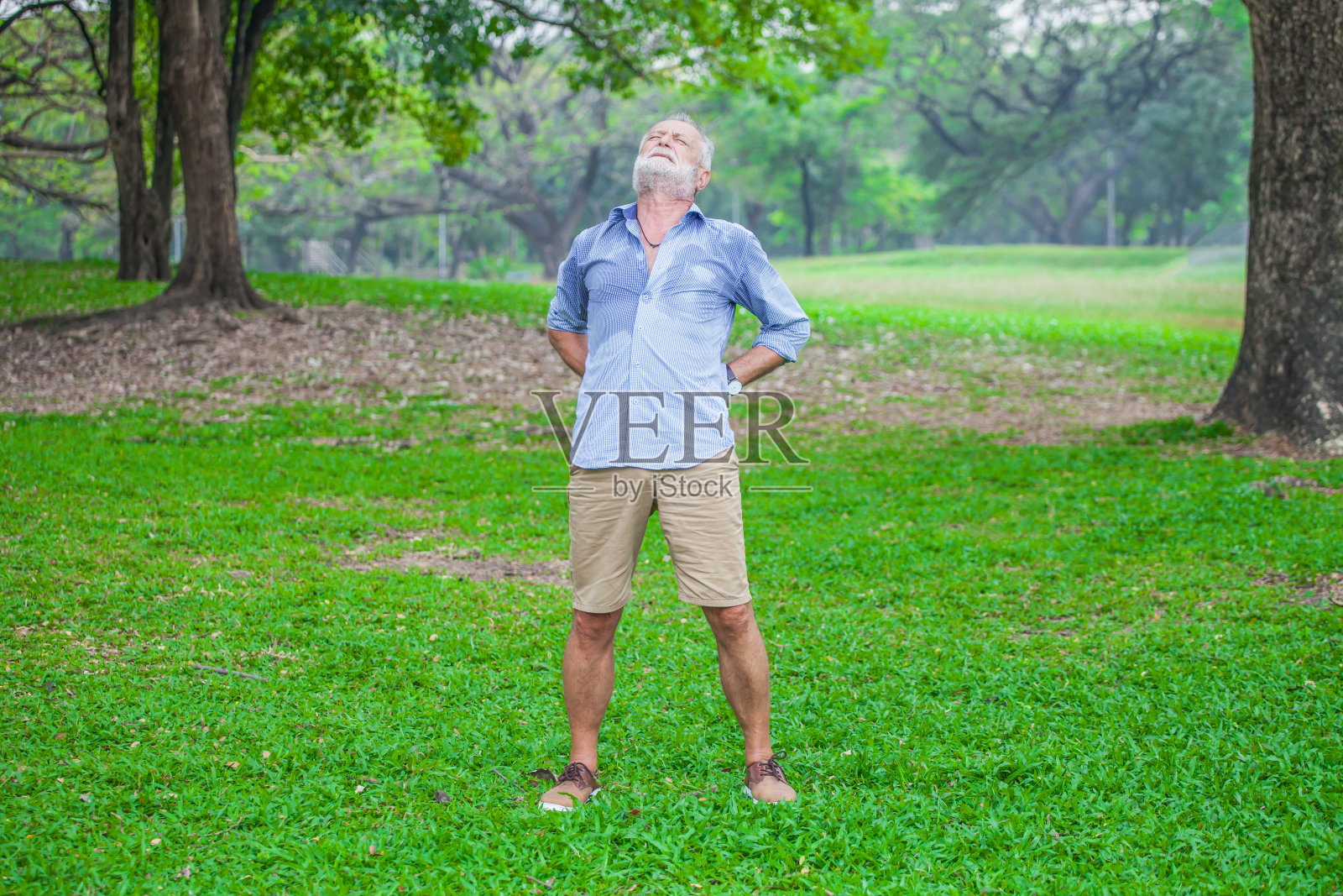 一位老人在自然公园散步时背部疼痛照片摄影图片