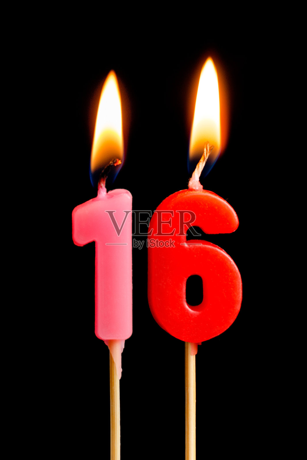 燃烧的蜡烛以16个数字(数字，日期)的形式为蛋糕孤立在黑色的背景。庆祝生日、周年纪念、重要日期、节日、餐桌摆设的概念照片摄影图片