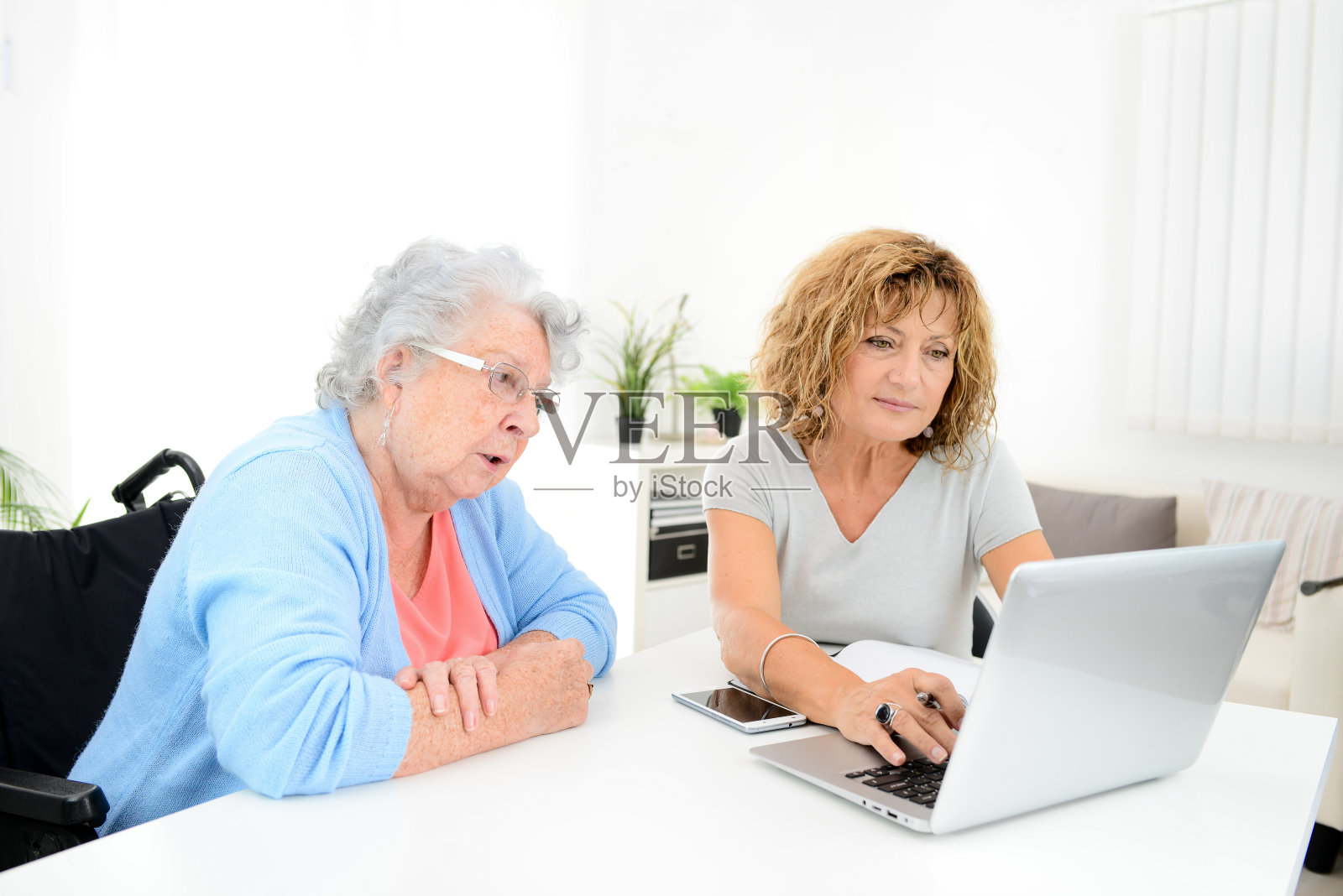 成年妇女在家用笔记本电脑协助年长女性办理行政手续和文书工作照片摄影图片