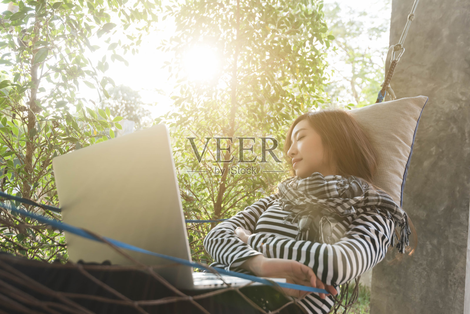年轻女子睡在吊床上，使用笔记本电脑，自由职业者的生活方式概念，工作在任何地方照片摄影图片