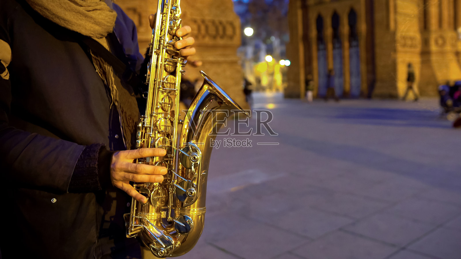 音乐家演奏萨克斯音乐，浪漫的氛围，在夜晚的城市约会照片摄影图片