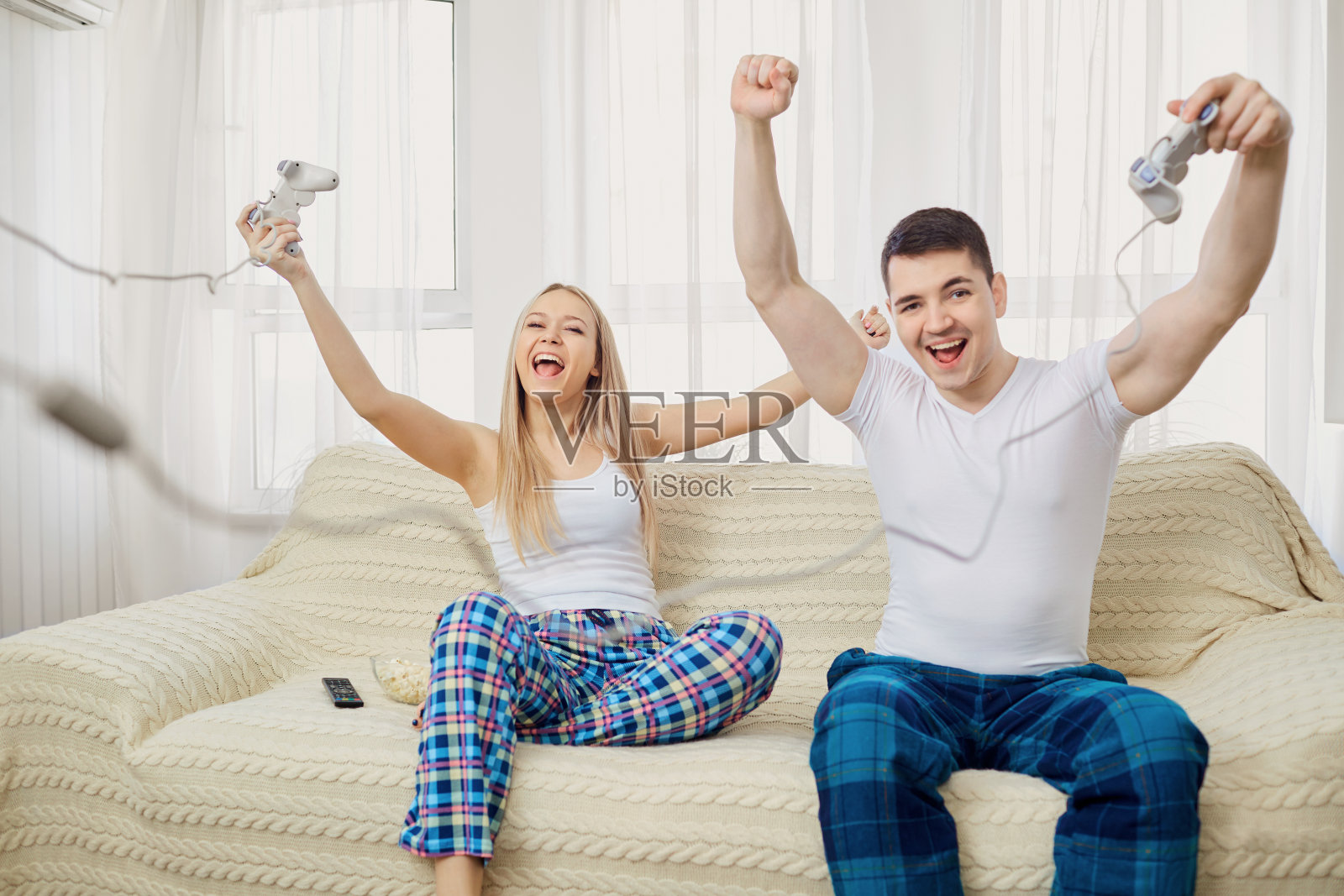一对夫妇坐在房间的沙发上玩电子游戏照片摄影图片
