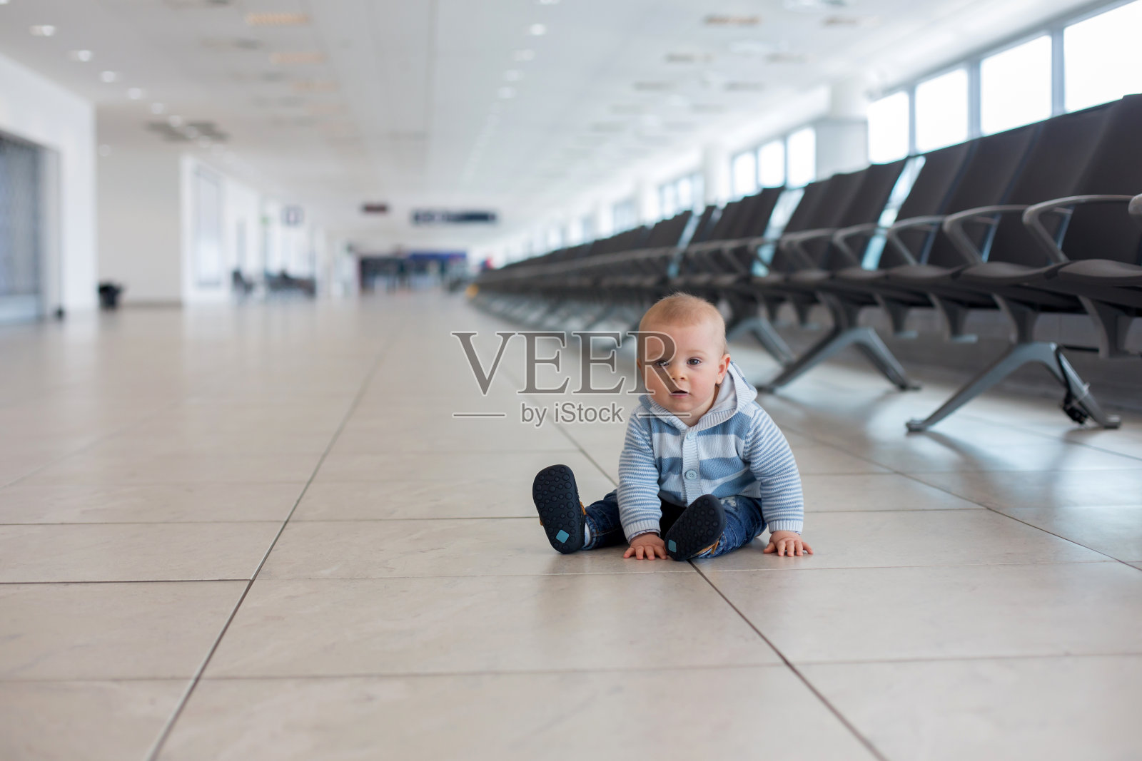 一个小孩，一个小男孩，在机场等待飞机起飞的时候玩耍照片摄影图片