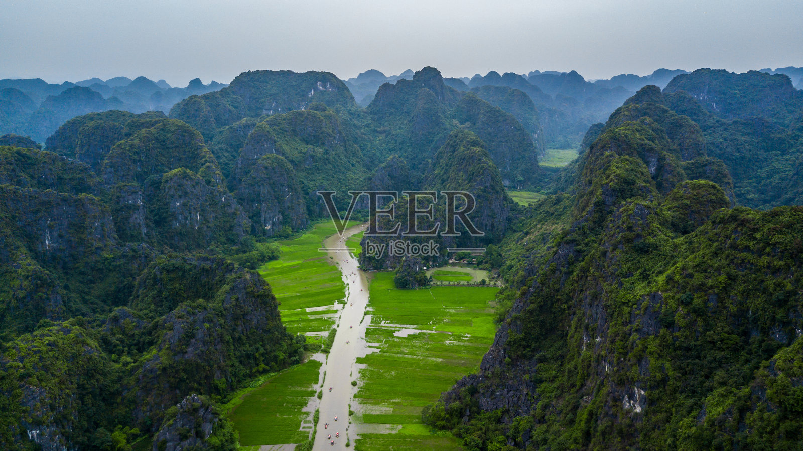 鸟瞰图游客乘船沿Ngo洞河旅行和拍照的Tam Coc，桨手用脚推进桨，Tam Coc，宁平，越南。照片摄影图片