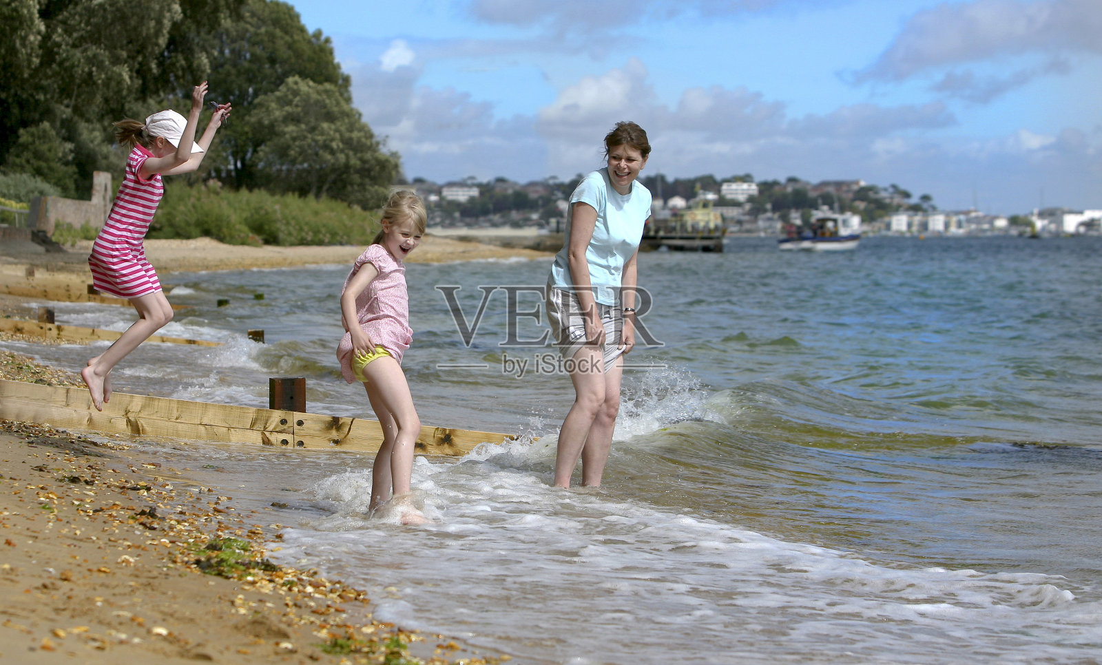母亲和女儿在小浪花中划桨，享受在英格兰南部海岸的海滩假日照片摄影图片