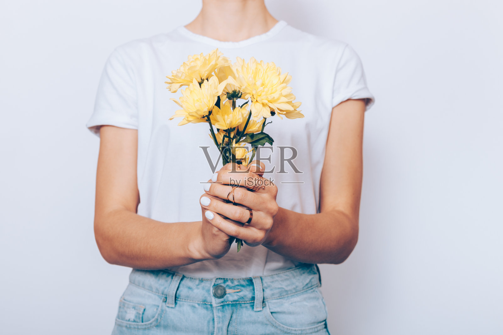 一个穿着t恤和牛仔裤的女人拿着一束黄色的花照片摄影图片