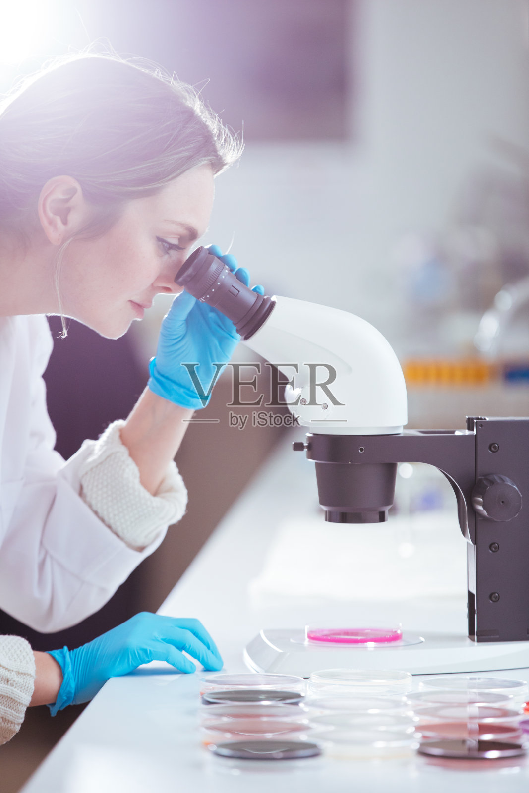 在实验室里通过显微镜观察的女科学家照片摄影图片