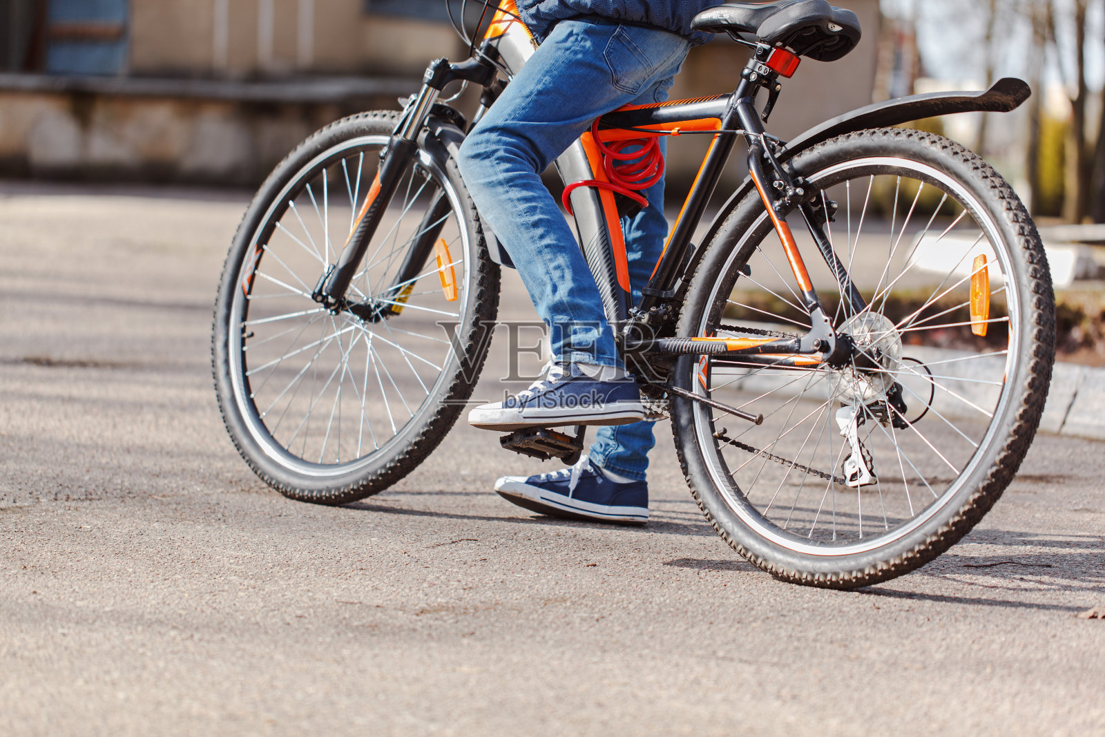 在阳光明媚的春日，孩子在柏油路上骑着自行车照片摄影图片