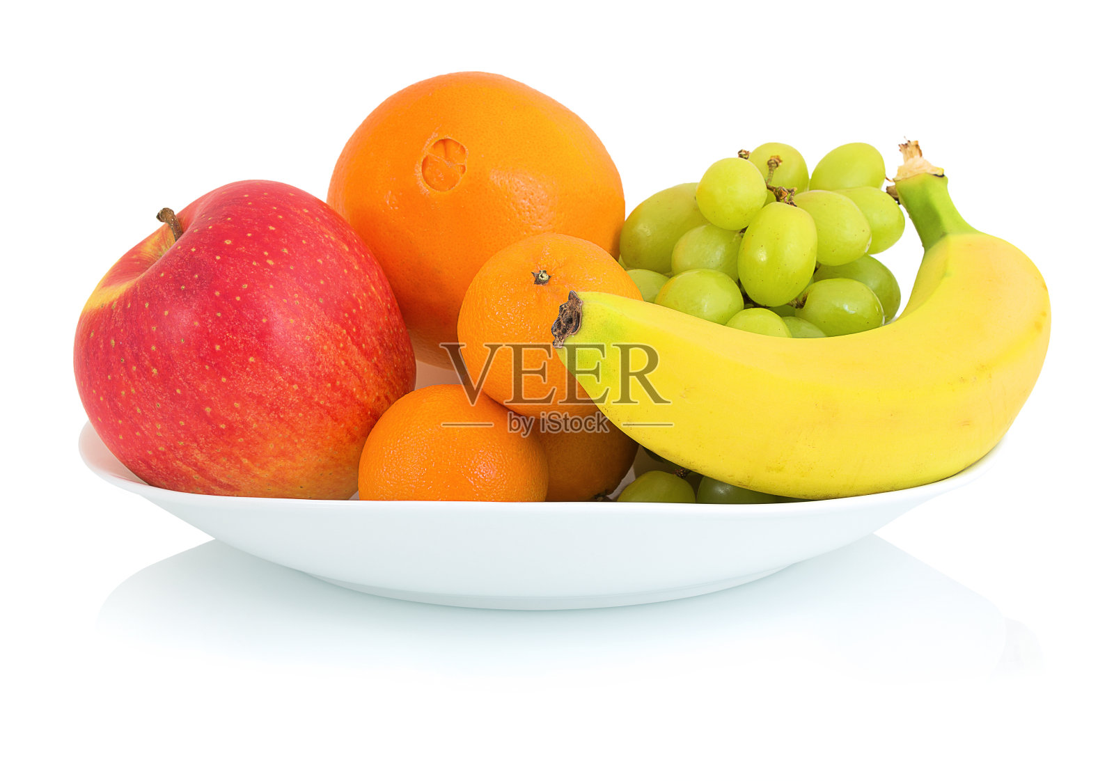 一碗鲜果孤立在白色背景与阴影反射。白碗里装着苹果、橘子、桔子、葡萄和香蕉。照片摄影图片